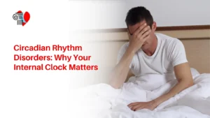 Exhausted man sitting in bed covering his face, representing sleep deprivation and circadian rhythm disorders.